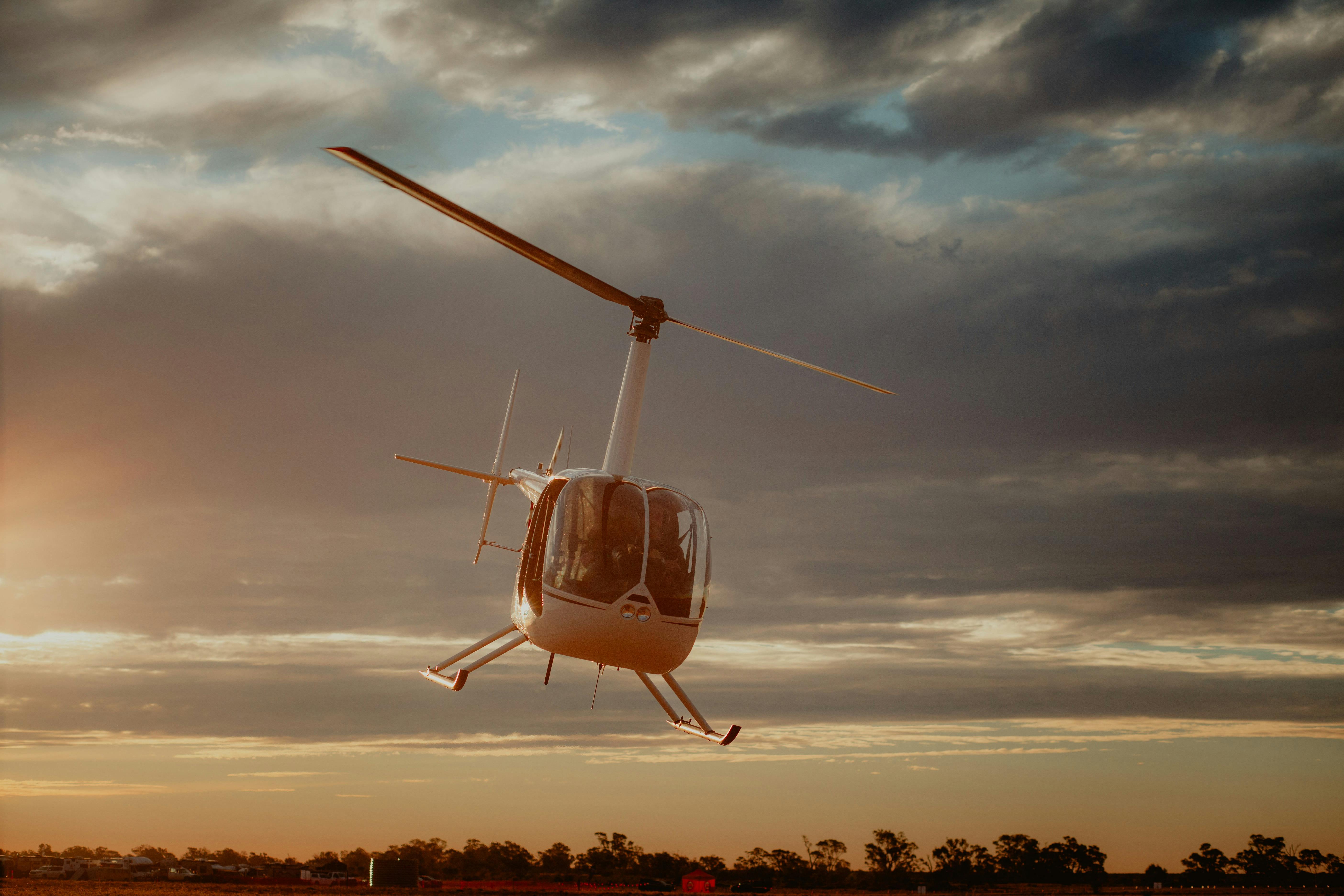 White helicopter flying at dusk with a cloudy sky background