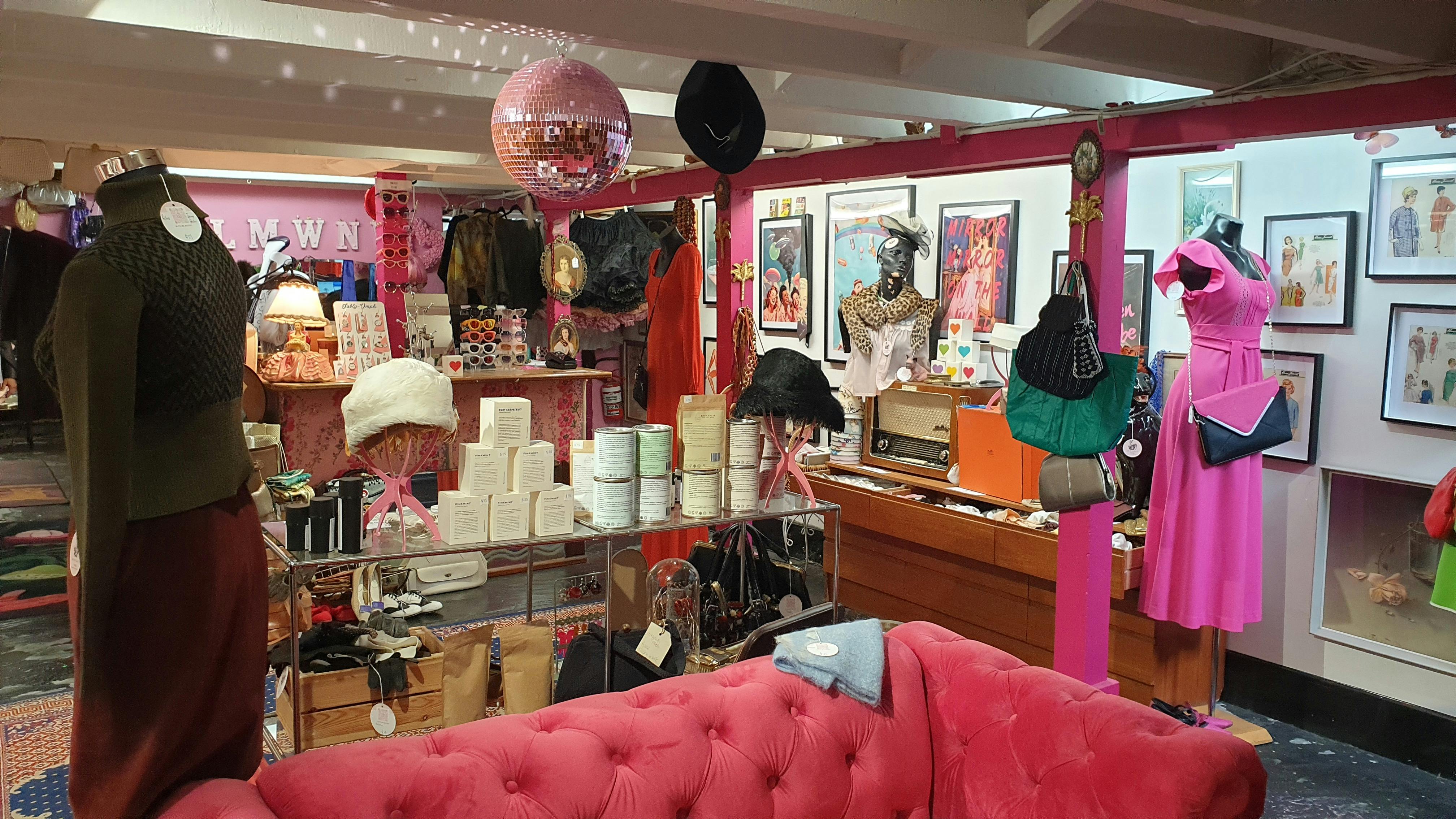 A pink couch is in a room also featuring shelves of jewellery and accessories, clothes and a counter