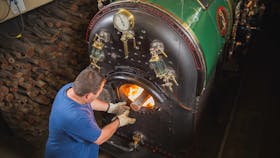 Engineer keeping steam up with Redgum logs