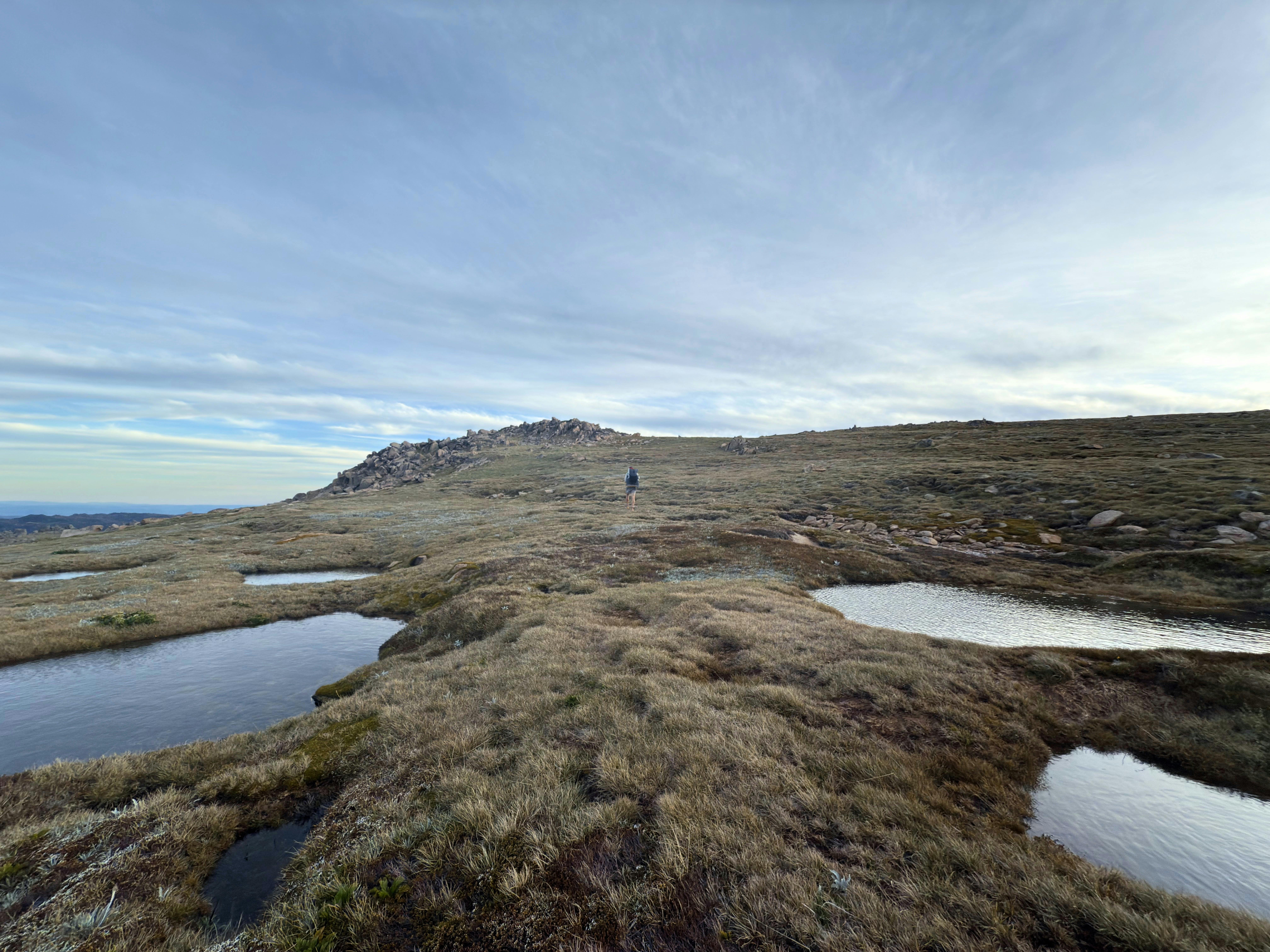 A few alpine bogs across rolling terrain with an overcast sky.