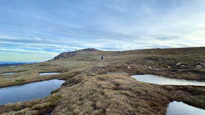 A few alpine bogs across rolling terrain with an overcast sky.