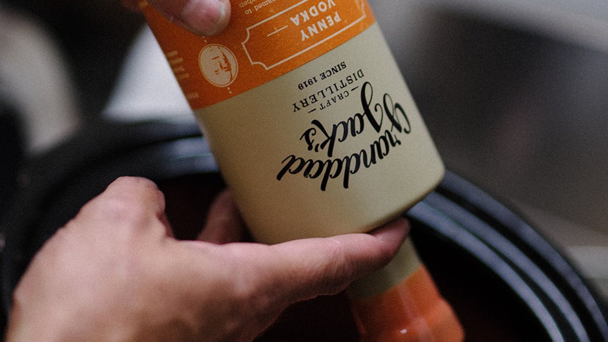 Dipping Penny Vodka bottle into the orange wax. Dipping Penny Vodka bottle into the orange wax.