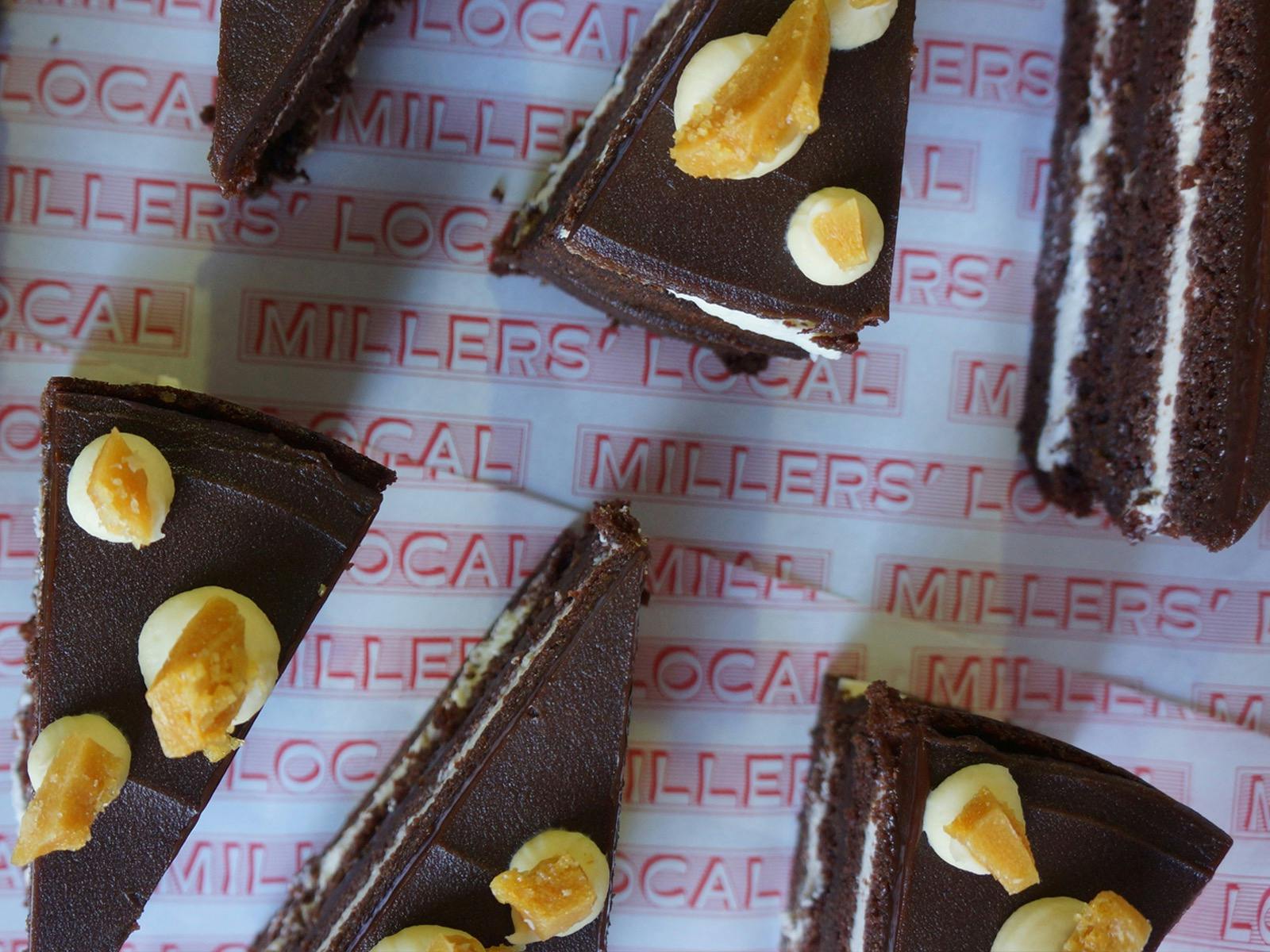 Pieces of chocolate cake with ganache, fresh whipped cream and macadamia brittle arranged diagonally