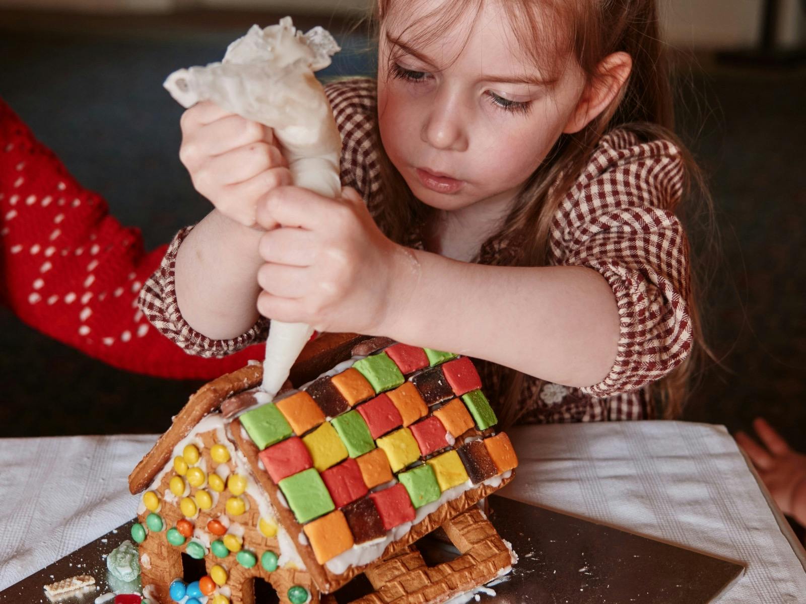 Gingerbread making class at Como House with girl piping icing on decorated house