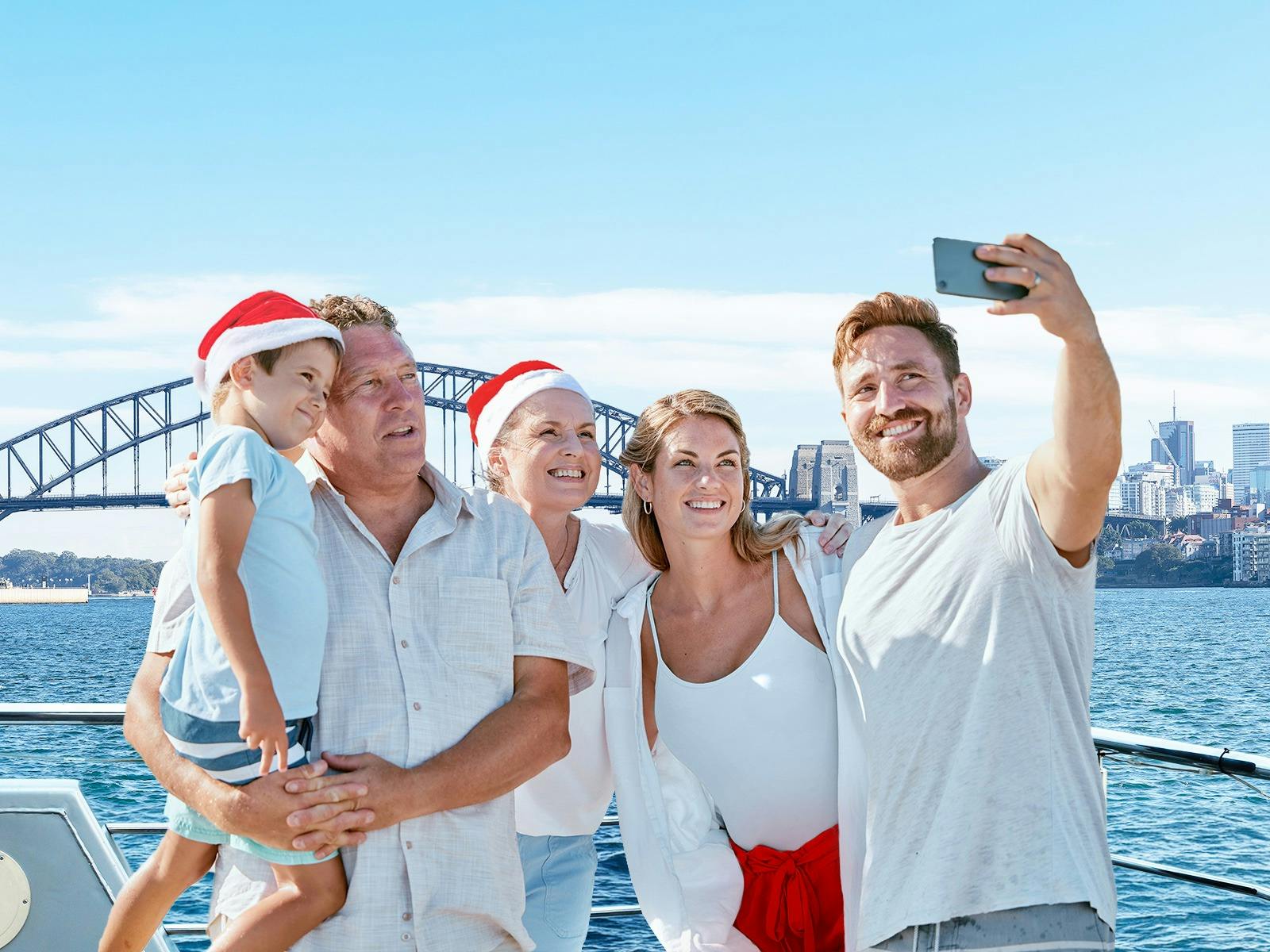 Family clicking a selfie on a cruise with the Harbour Bridge as backdrop.
