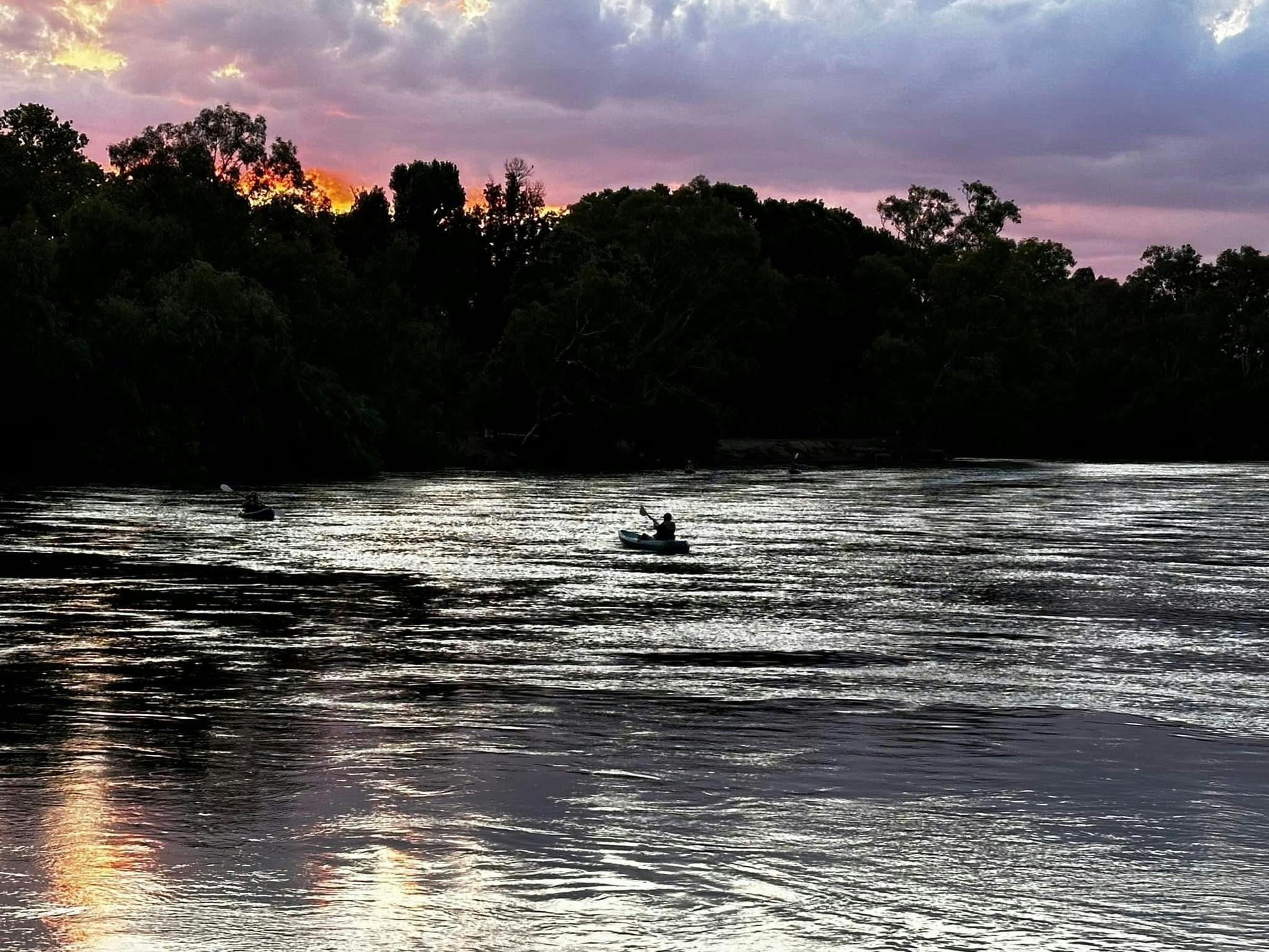 Paddlers on the river at dusk