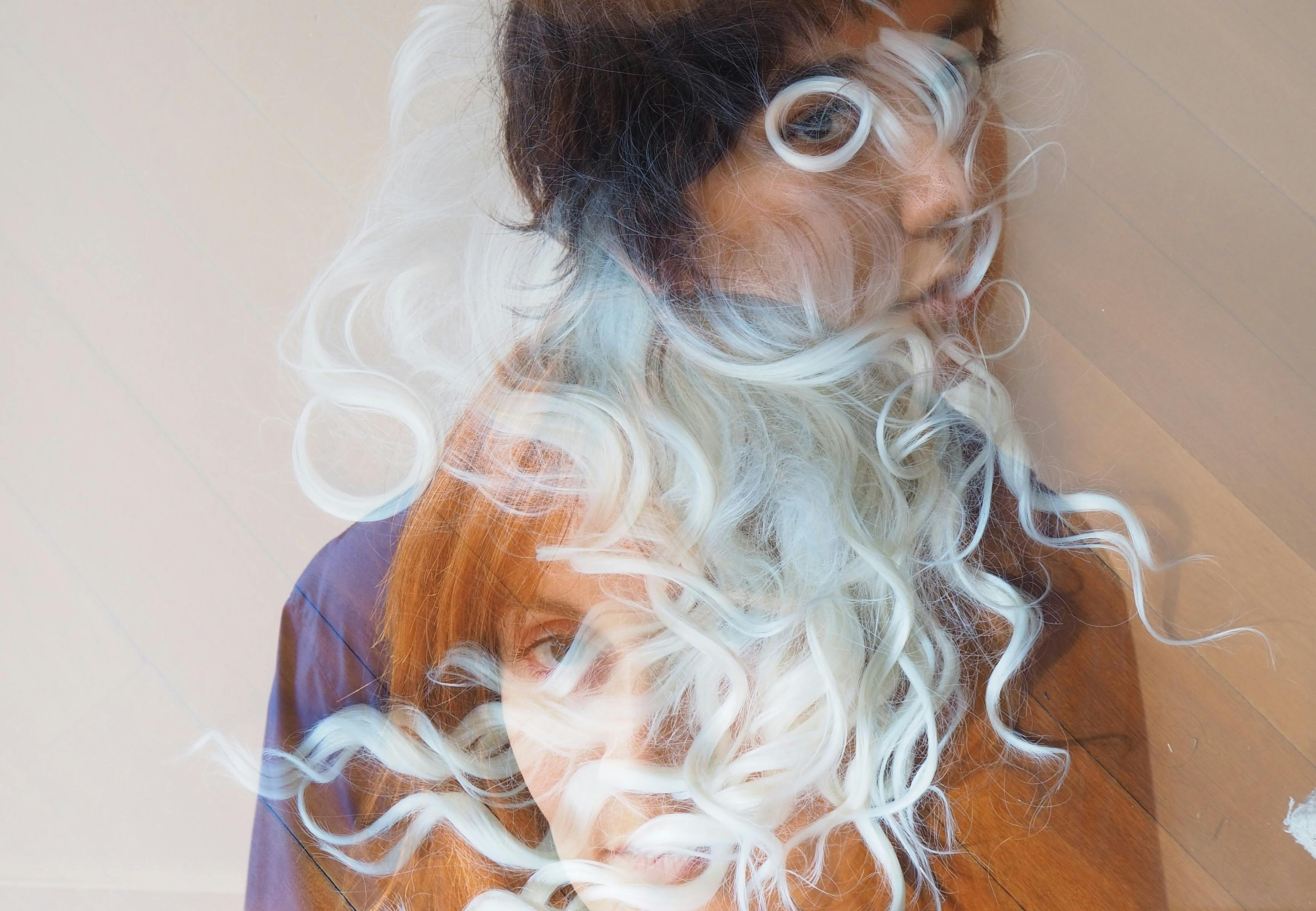 A multiple exposure image of two people in wigs.