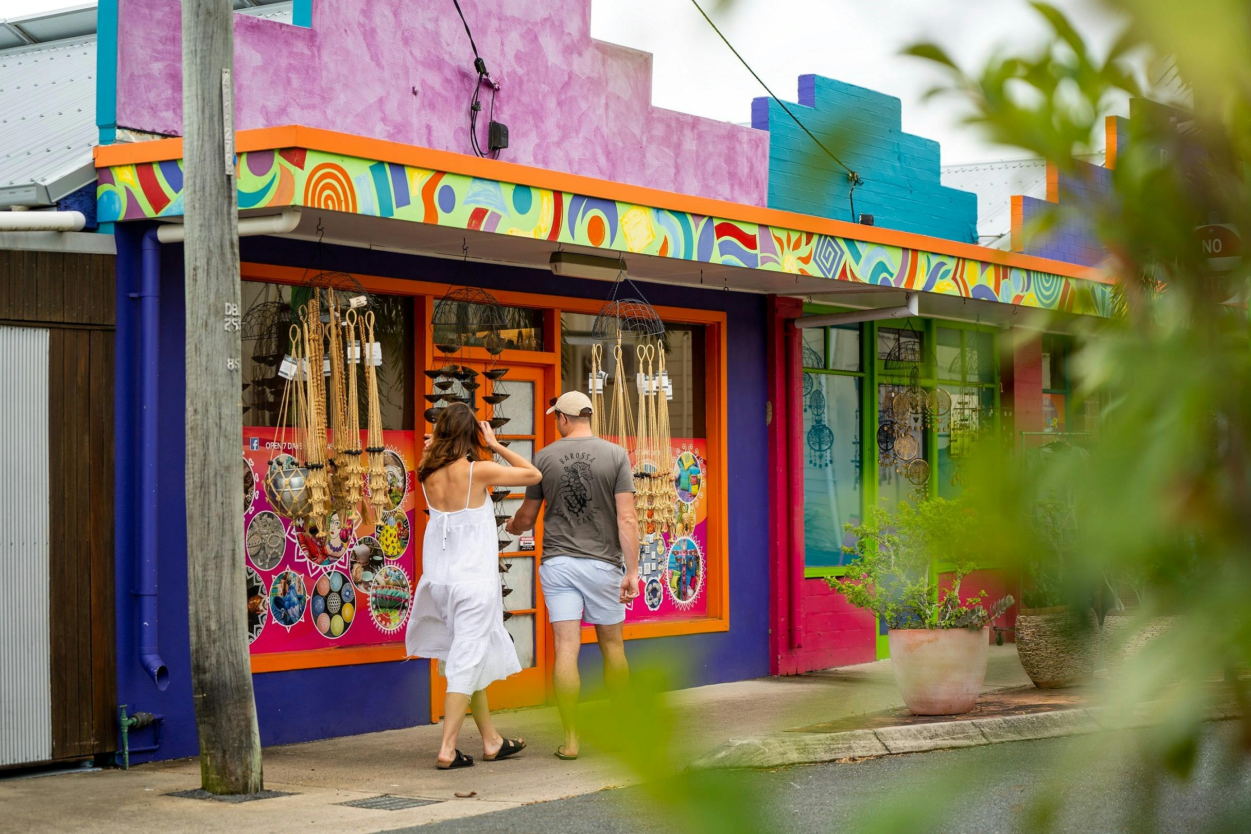 A couple passing by a colorful shop on the street