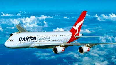 Qantas aircraft flying through blue sky and clouds