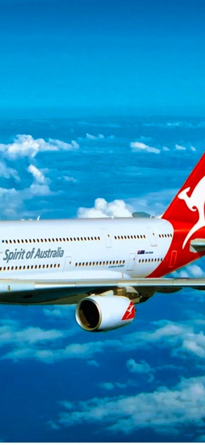 Qantas aircraft flying through blue sky and clouds