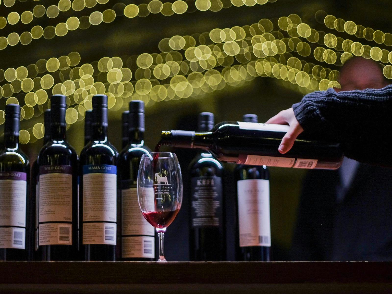 wine being poured into a glass under fairy lights