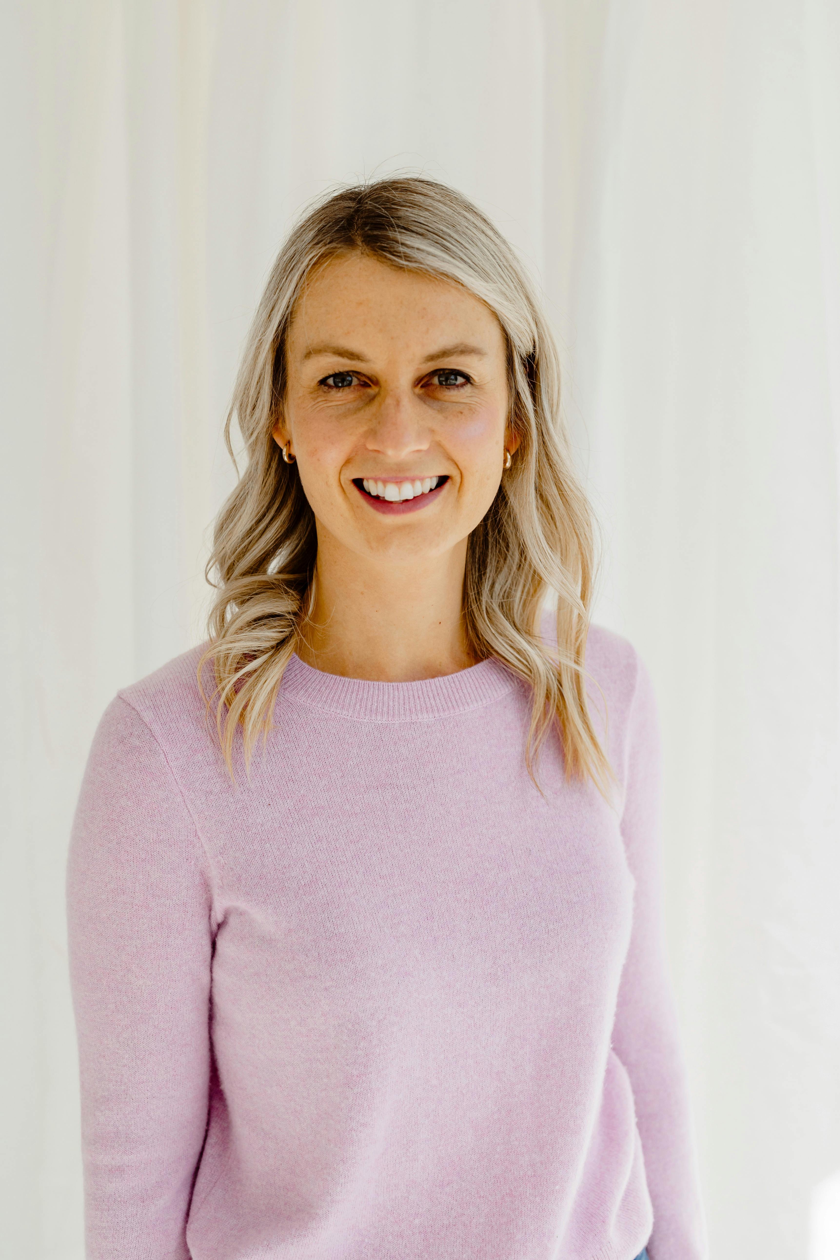 Smiling young lady with medium length blonde hair and mauve top