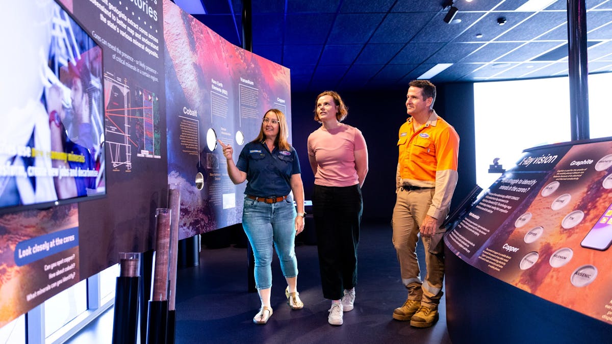3 adults looking at the critical minerals exhibit