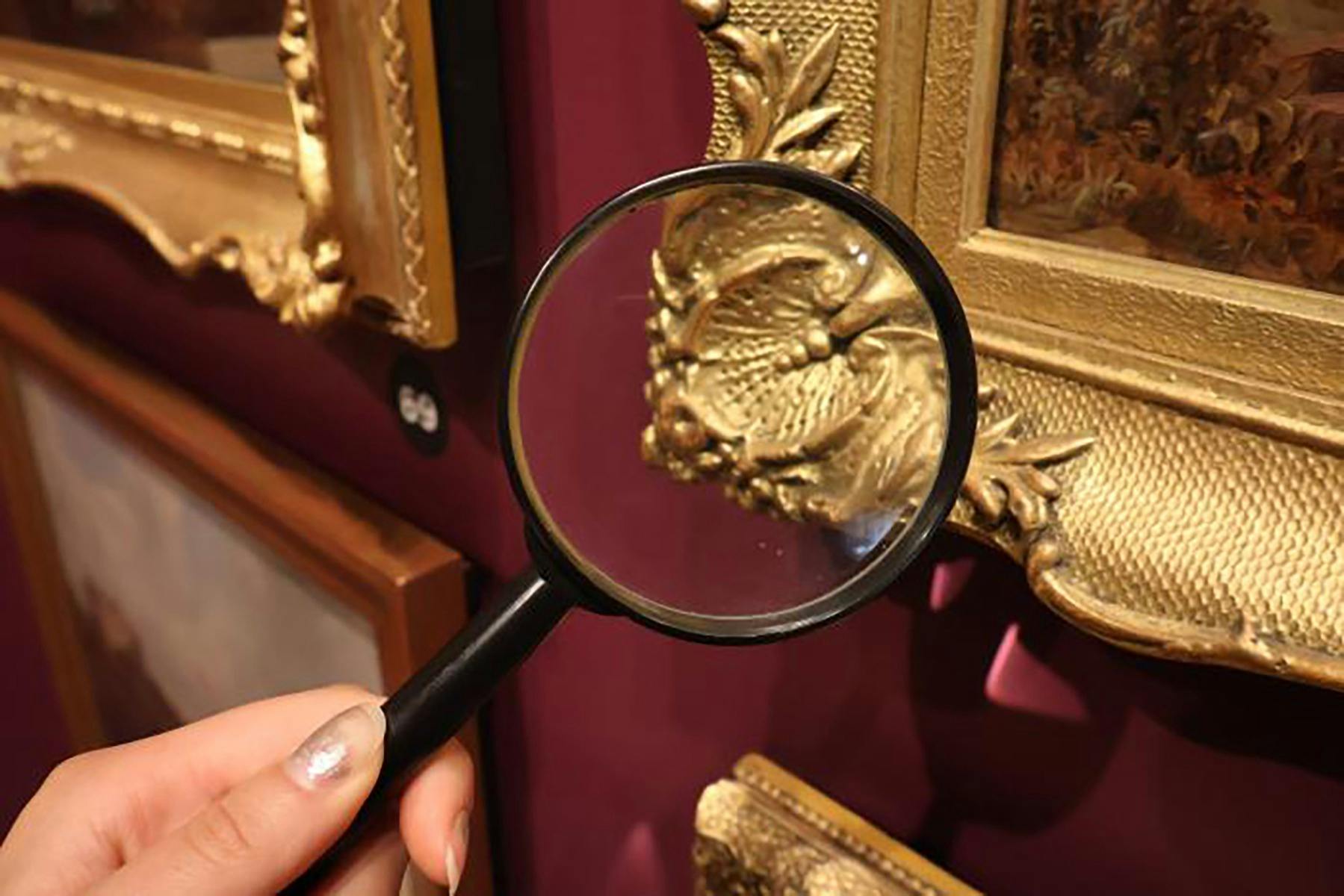 A magnifying glass held up to a gold frame
