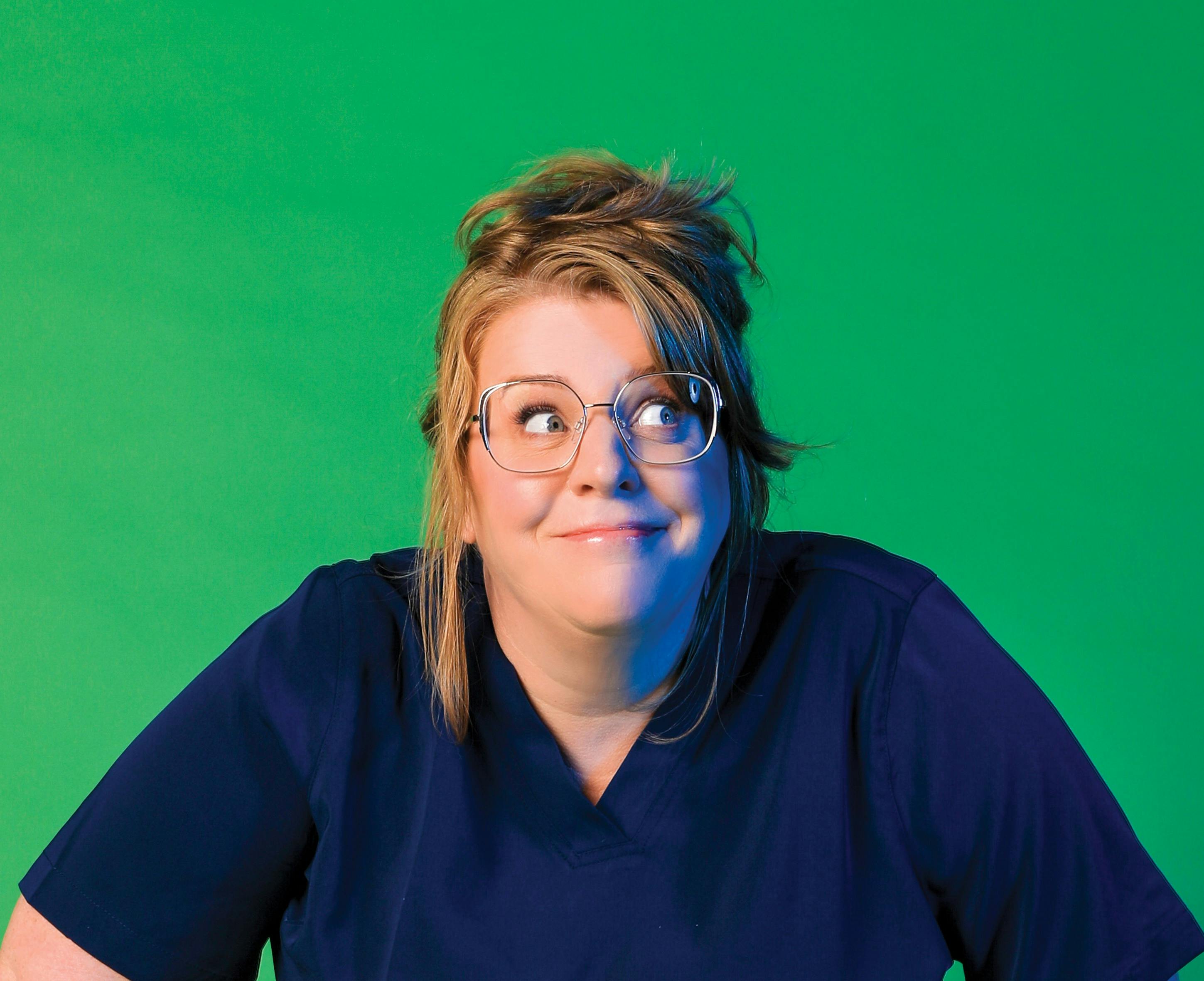 Georgie Carroll with messy hair wearing scrubs