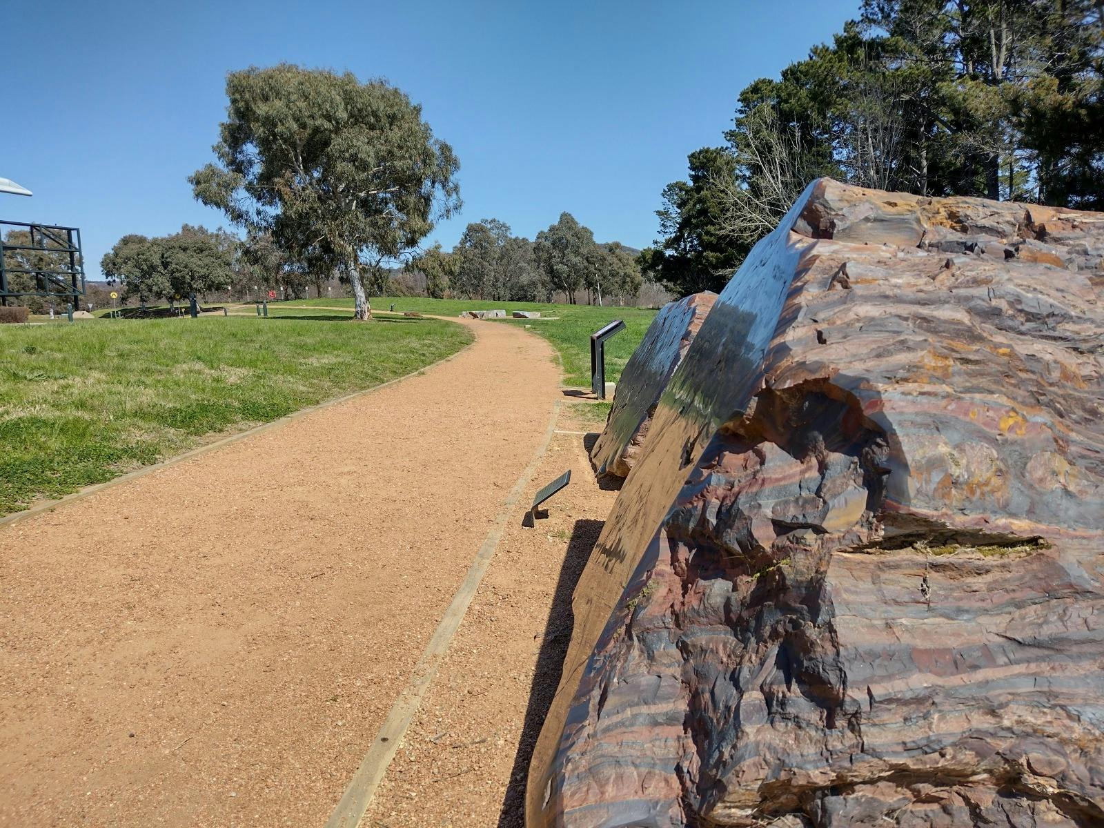 An outdoor gravel path stretches off into the distance. A striped red and black rock is next to it.