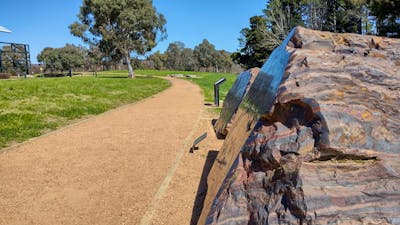 An outdoor gravel path stretches off into the distance. A striped red and black rock is next to it.