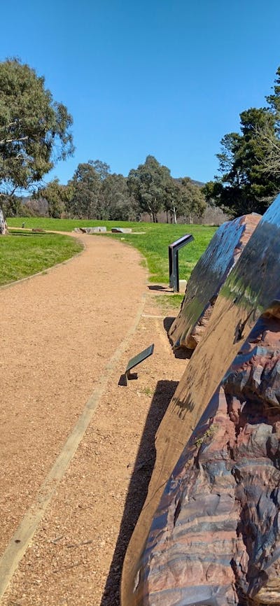 An outdoor gravel path stretches off into the distance. A striped red and black rock is next to it.