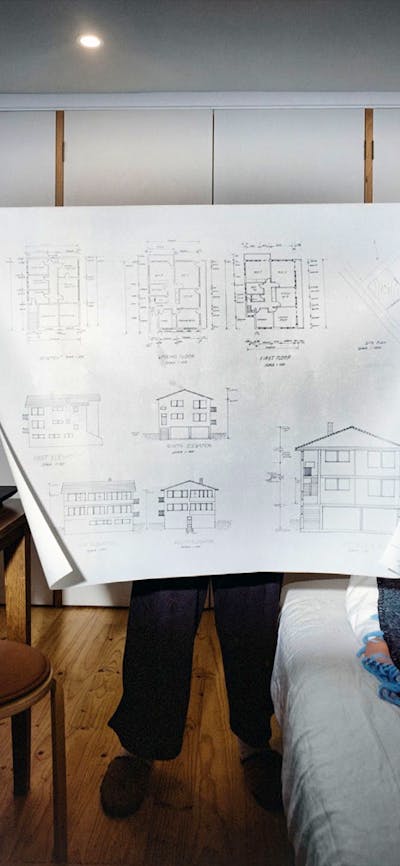 woman holding an architectural drawing in a bedroom