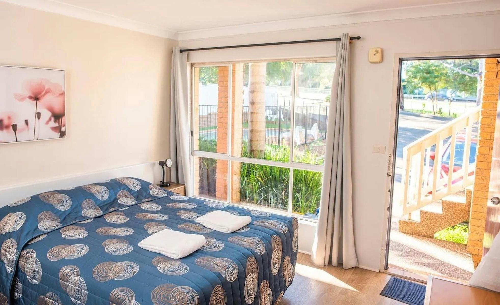 Ground floor queen room with view of swimming pool and parking area at Sutherland Motel