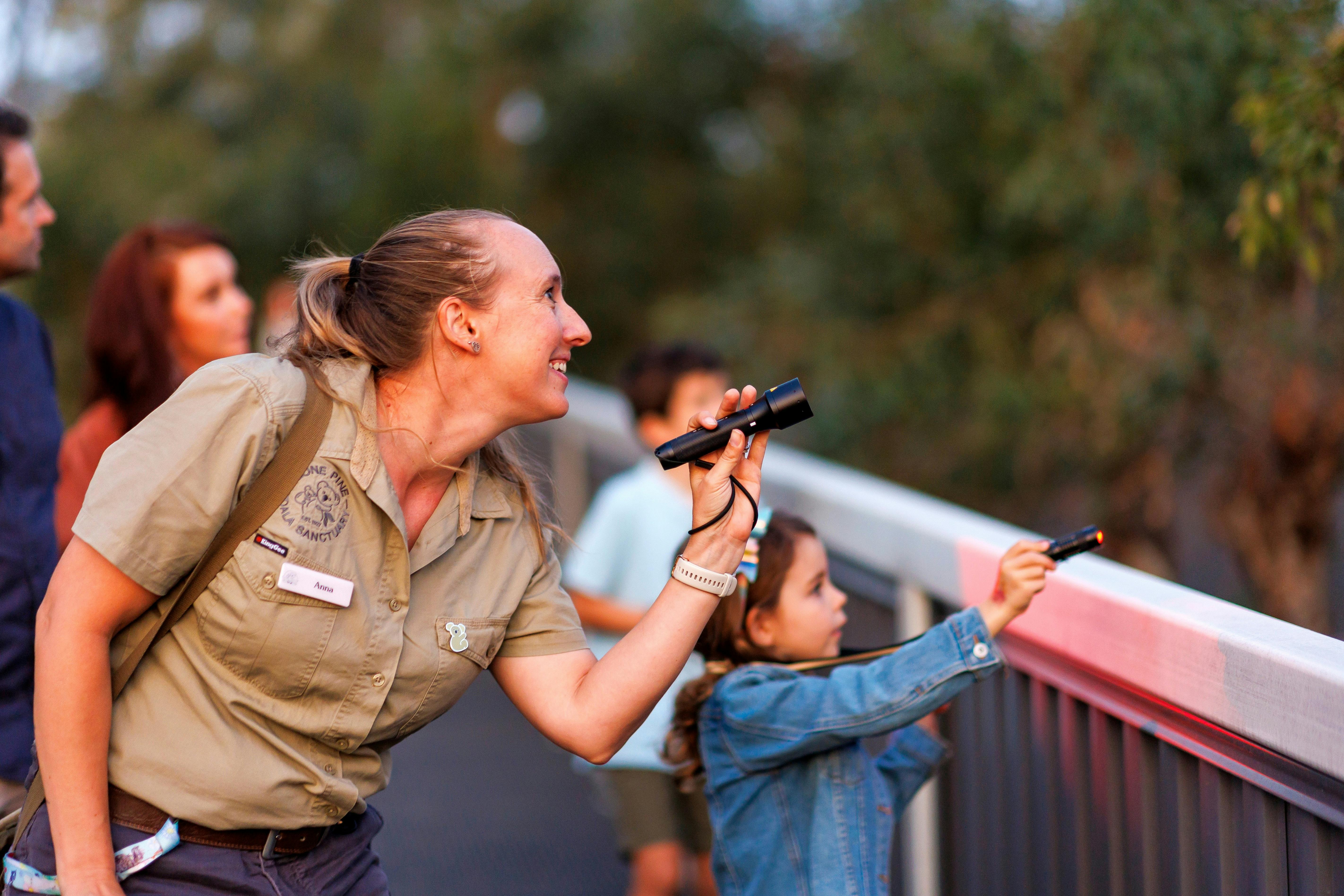 Wildlife keeper and young girl spotting Australian wildlife at dusk