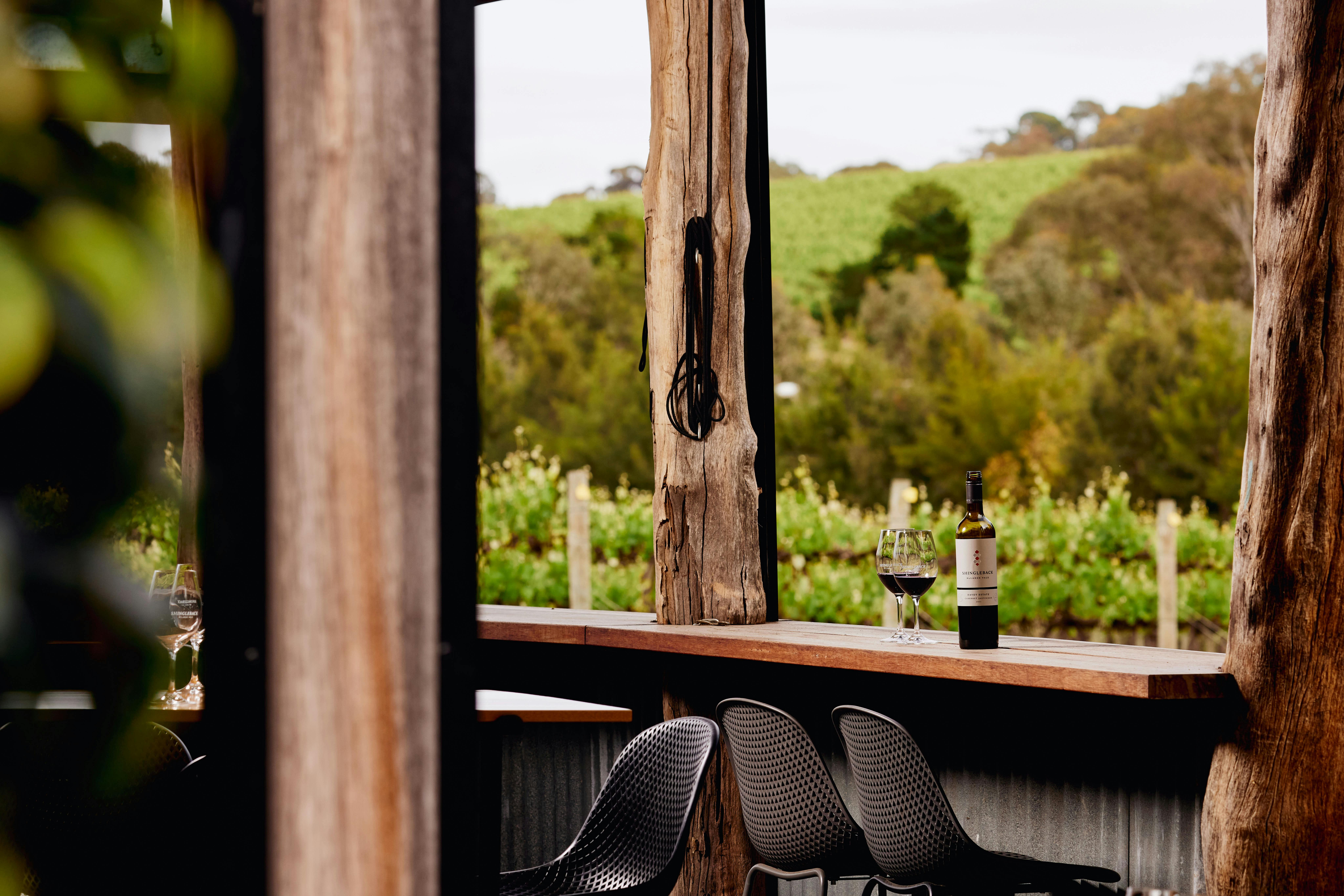 The rustic verandah at Shingleback Cellar Door, a bottle of red wine waiting for guests to sip.