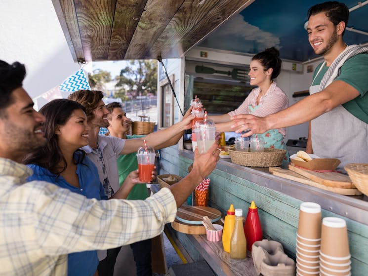 A group of people buying food from a food truck.