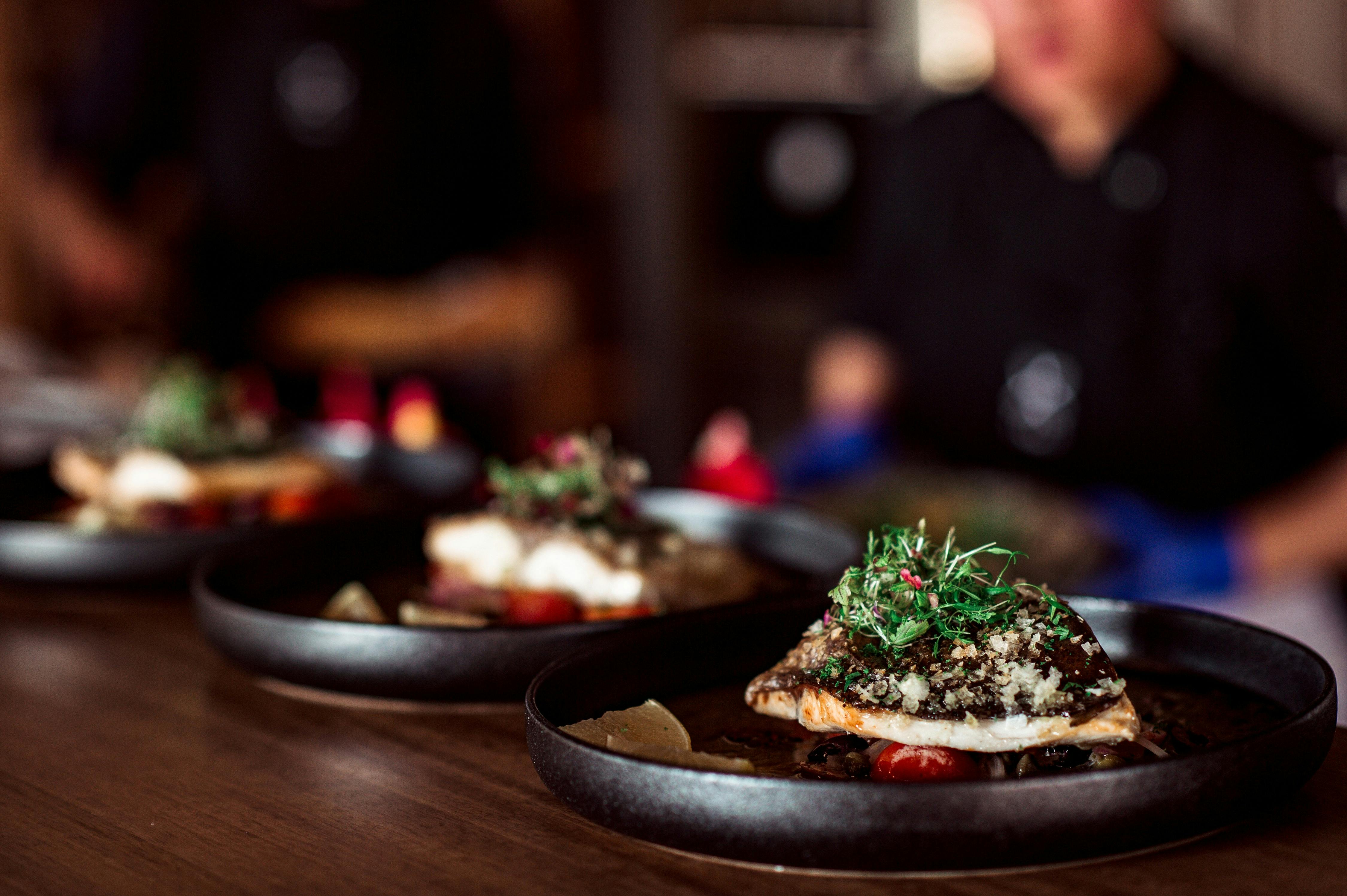 A line up of three black plates with different meals