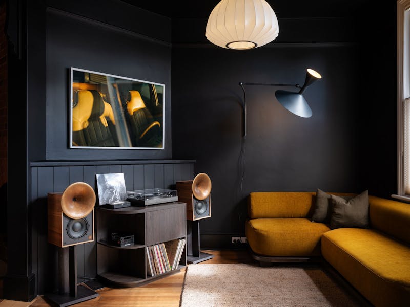 Dark lounge room with bronze speakers, record player and couch.