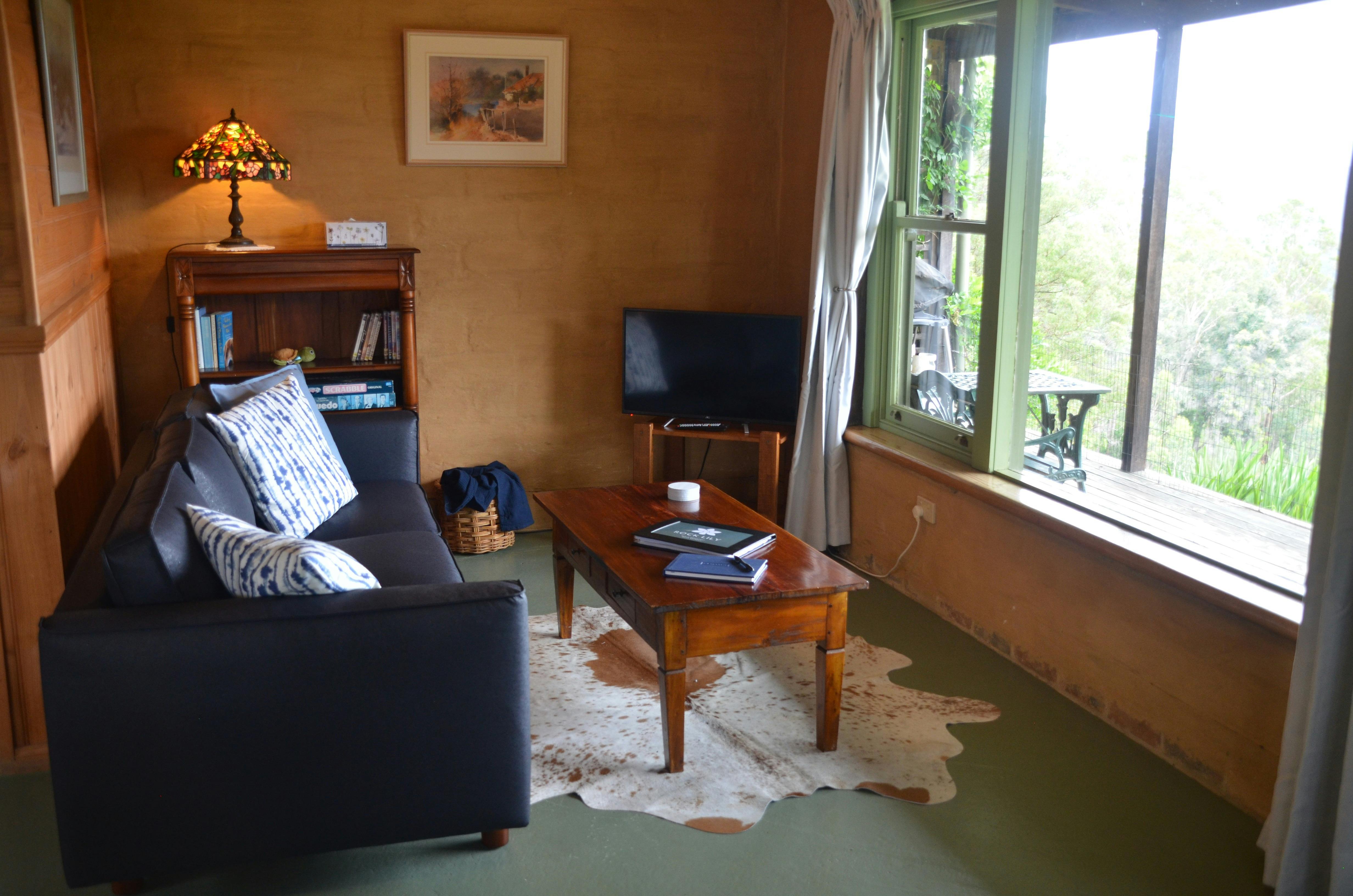 A black sofa near to a coffee table, bookcase, and TV table.