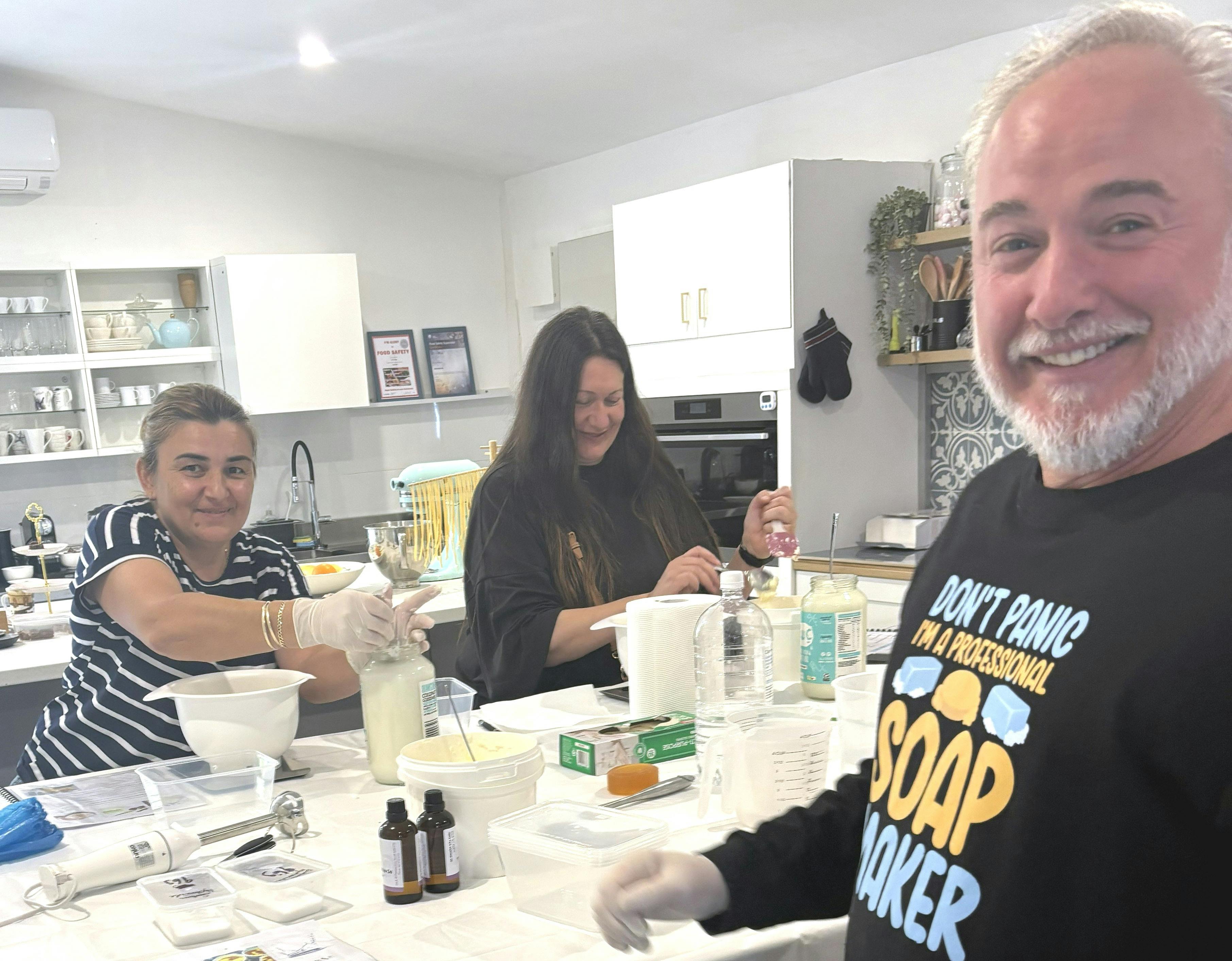 Soap making teacher smiling while students enjoy making soap