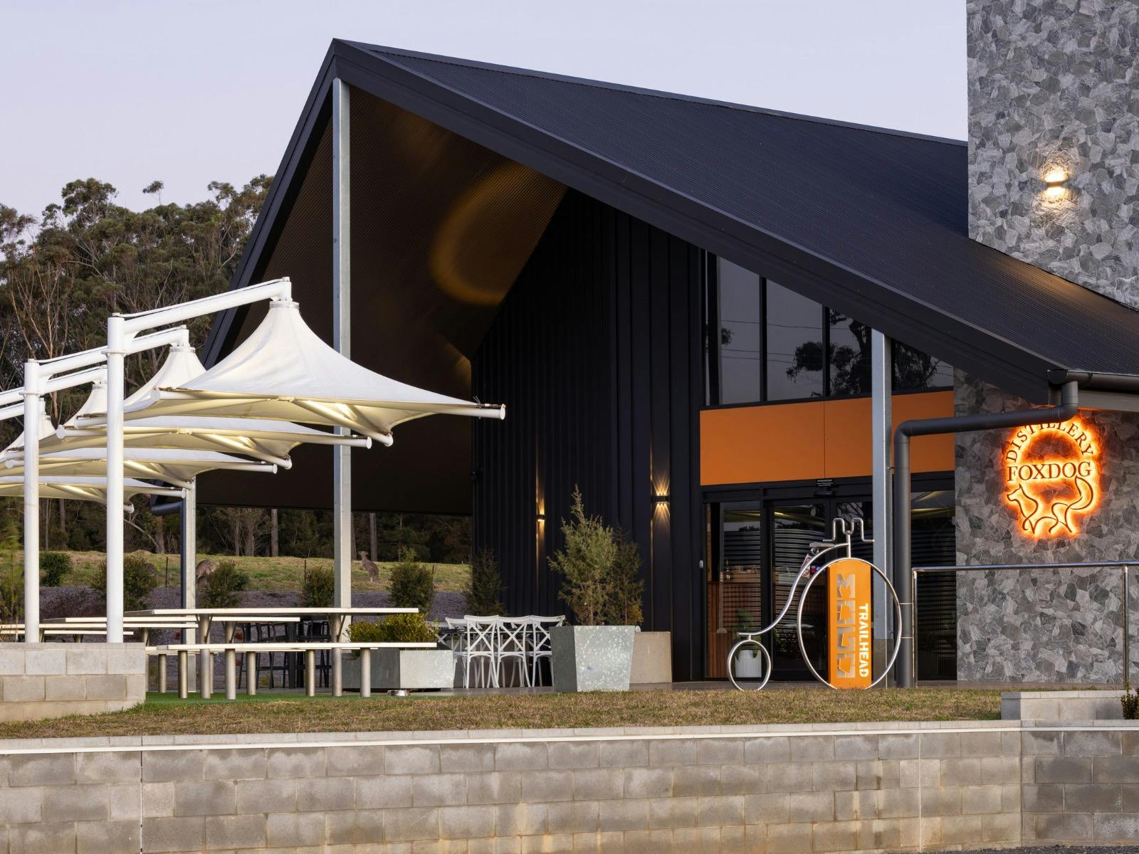 Exterior view of Foxdog Distillery & Brewery at dusk, featuring its modern black and stone building