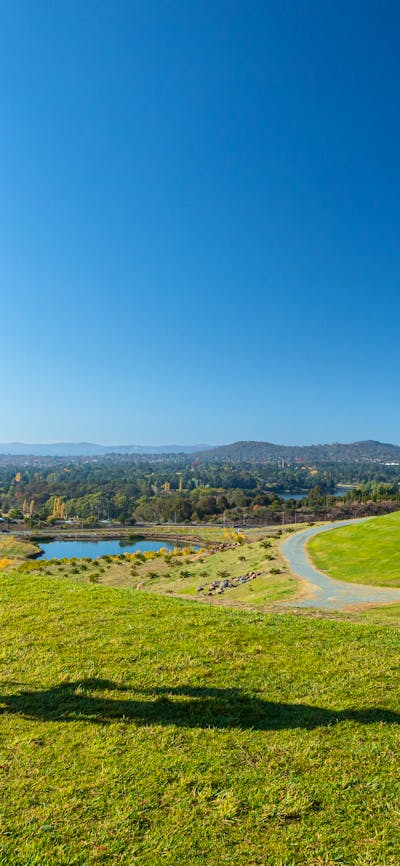 an artists easel with an artwork in front of a view of canberra and lake burley griffin