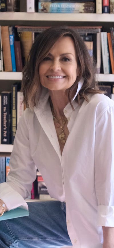 A woman sitting on a stool with a bookcase behind her