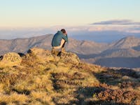 A hiker capturing the golden hour on his camera from the top of Mt Stirling.