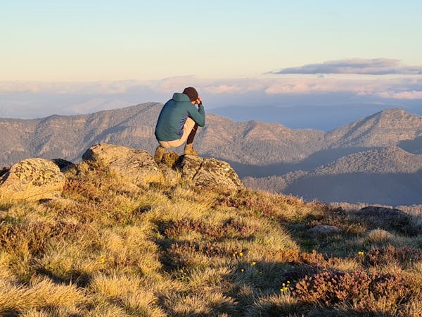A hiker capturing the golden hour on his camera from the top of Mt Stirling.