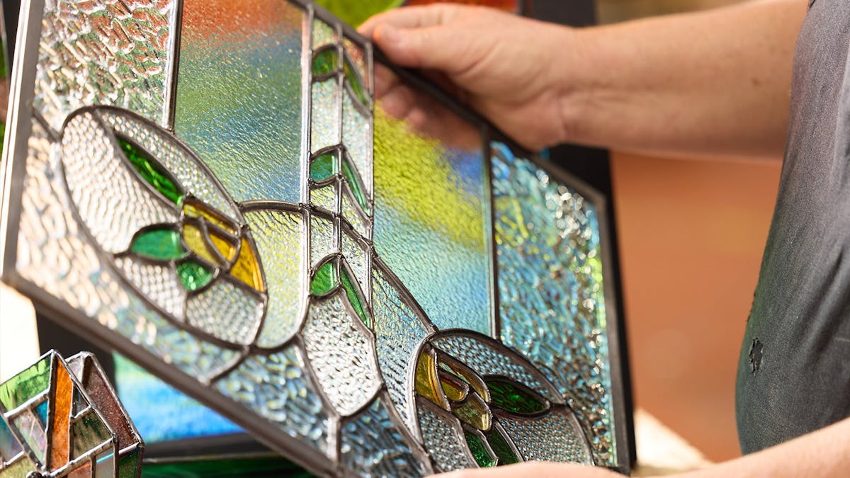 Person holding stained glass panel.