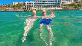 A father and daughter take a break in the water with the famous Icebergs in the background.