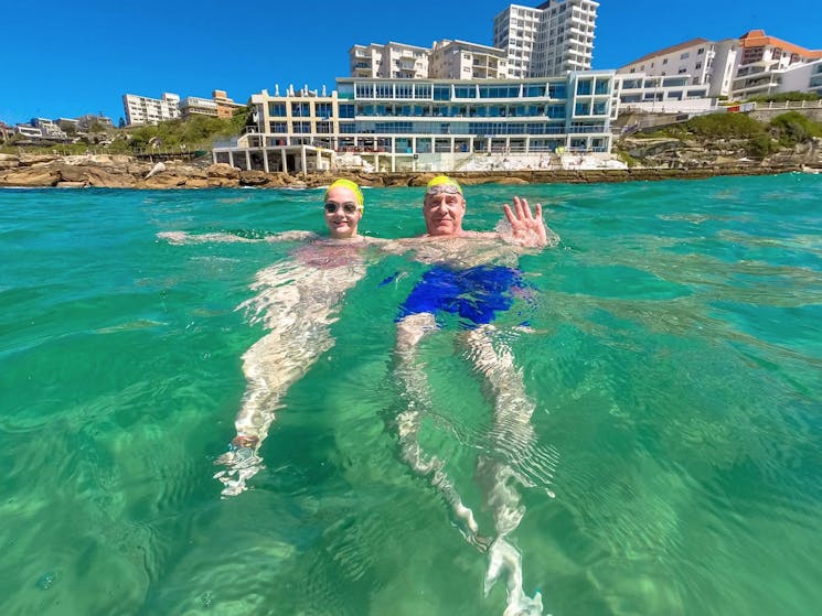 A father and daughter take a break in the water with the famous Icebergs in the background.