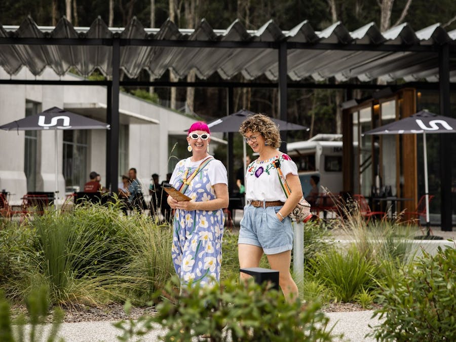 Two women walking down the pathway with Ramox Cafe and the Art Museum in the background