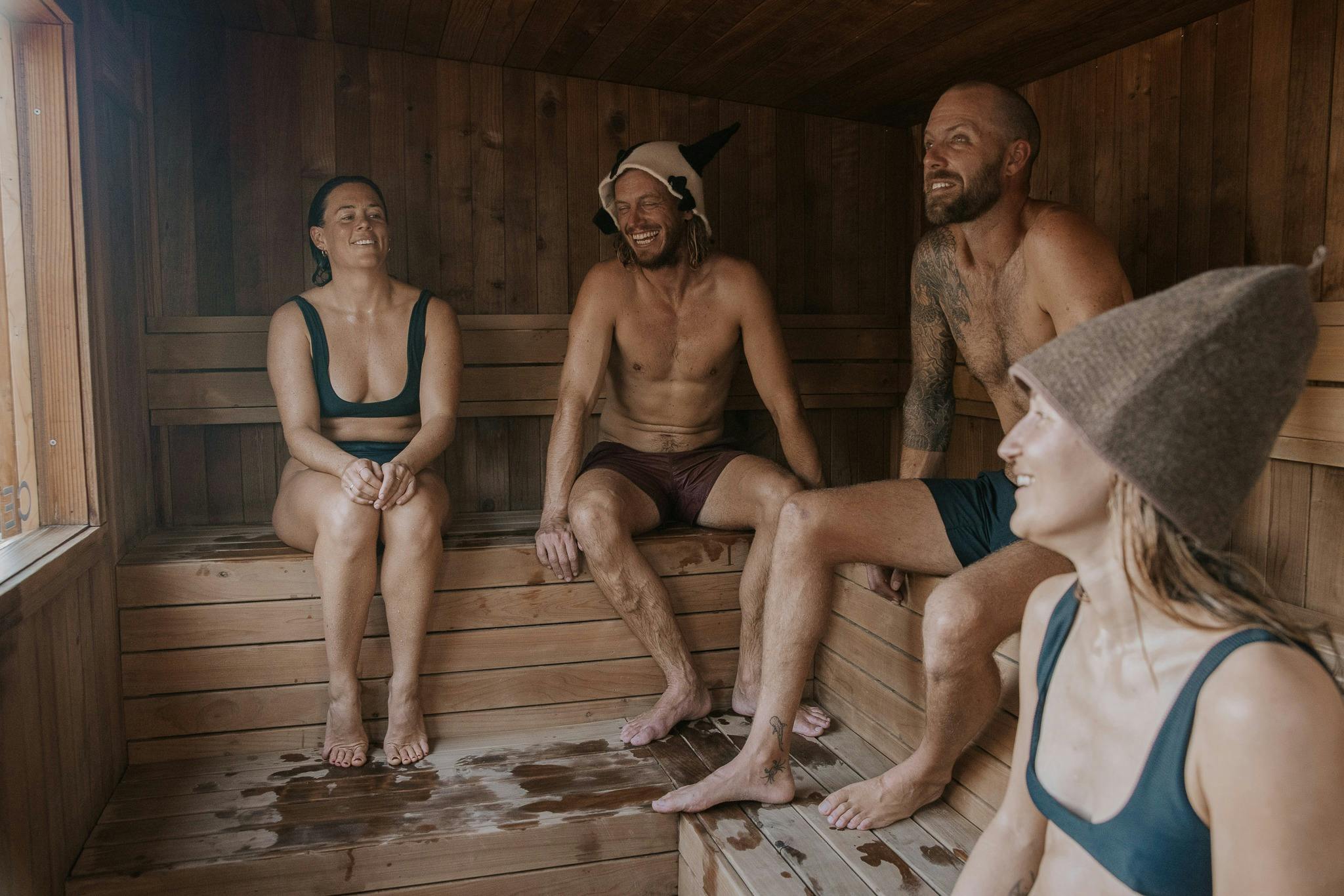 4 friends enjoying a beachside woodfire sauna in manly sydney