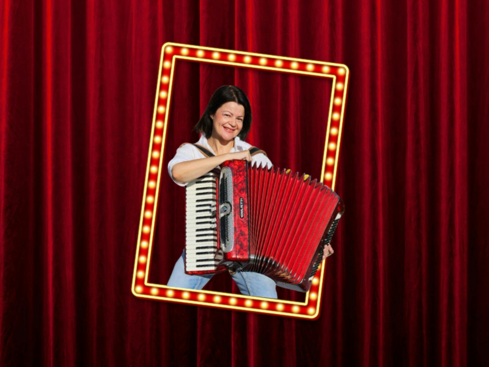 A person plays a red accordion, smiling inside a lit-up frame with marquee lights.
