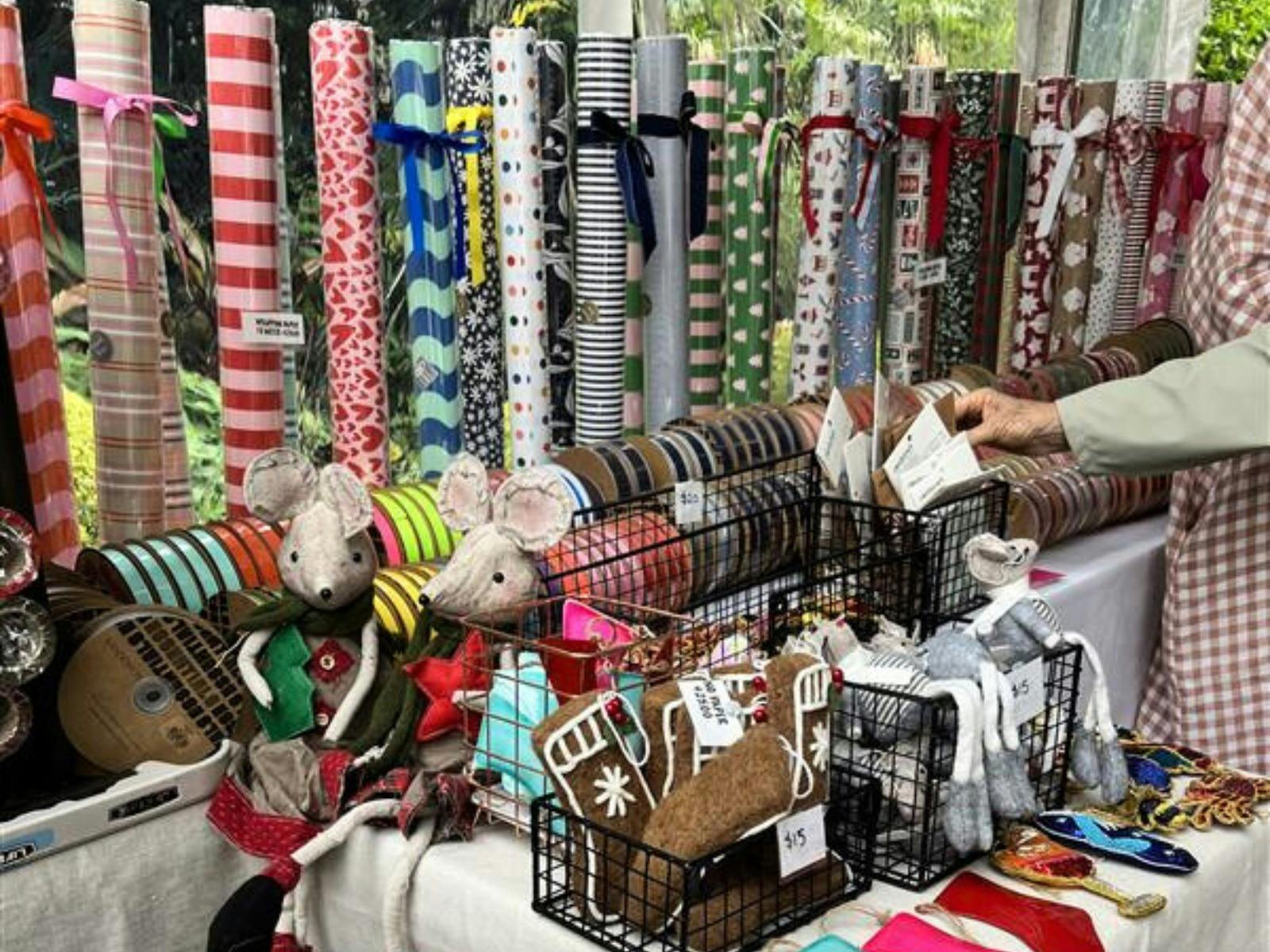 Colourful ribbon and wrapping paper on display. A hand extends from the right hand corner to pick up