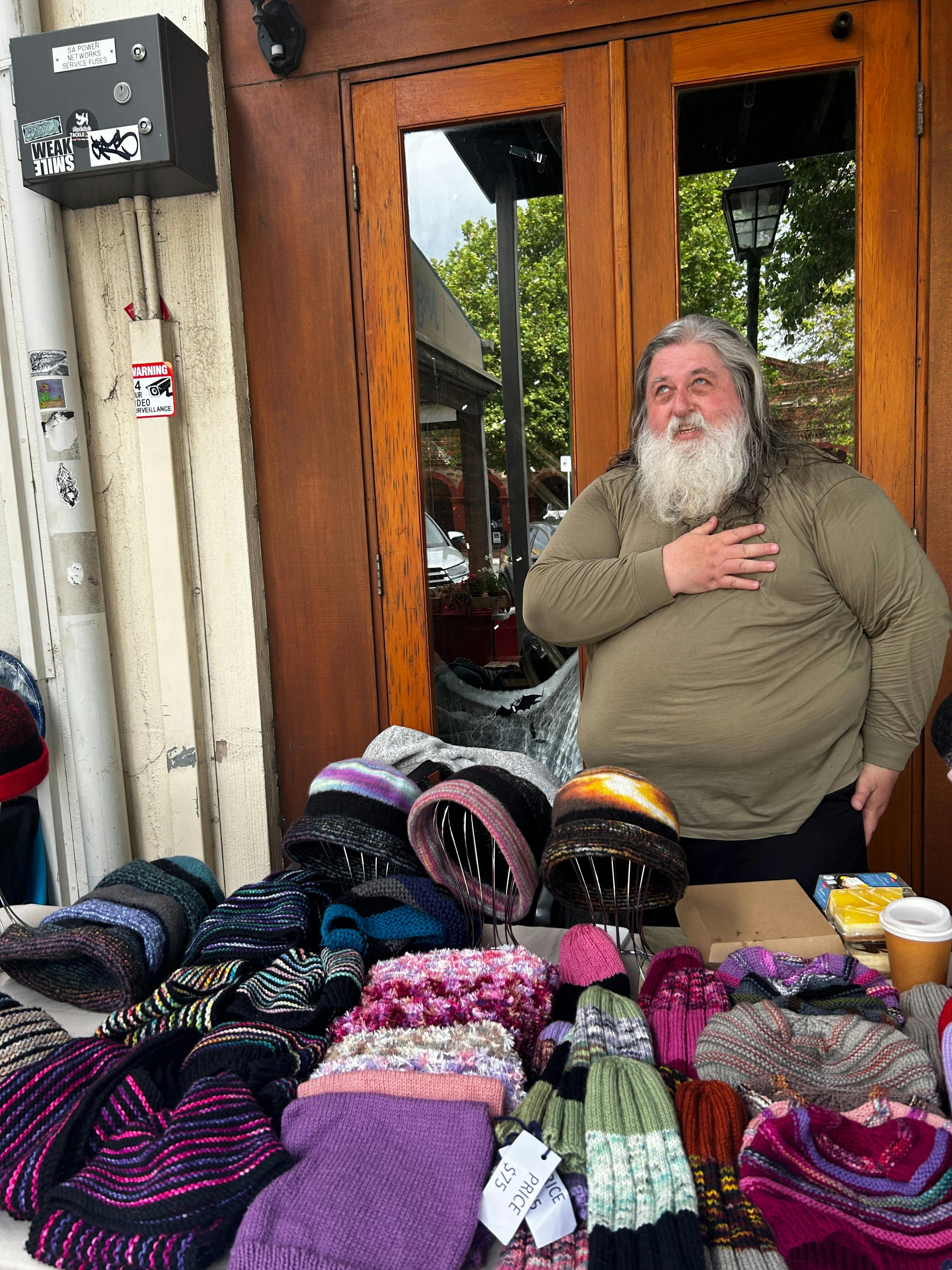 Local maker presenting handmade knitted beanies and scarves at Meandering Markets.