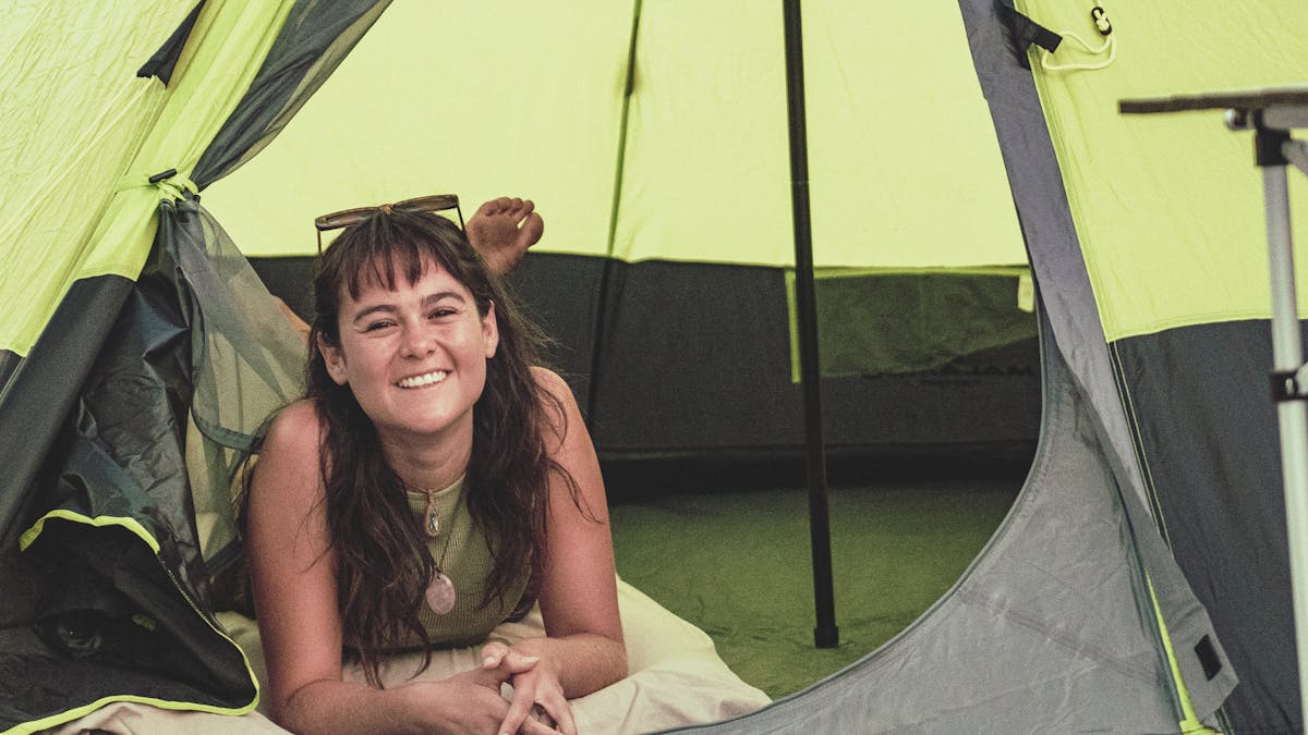 Happy girl laying and looking out of her tent door
