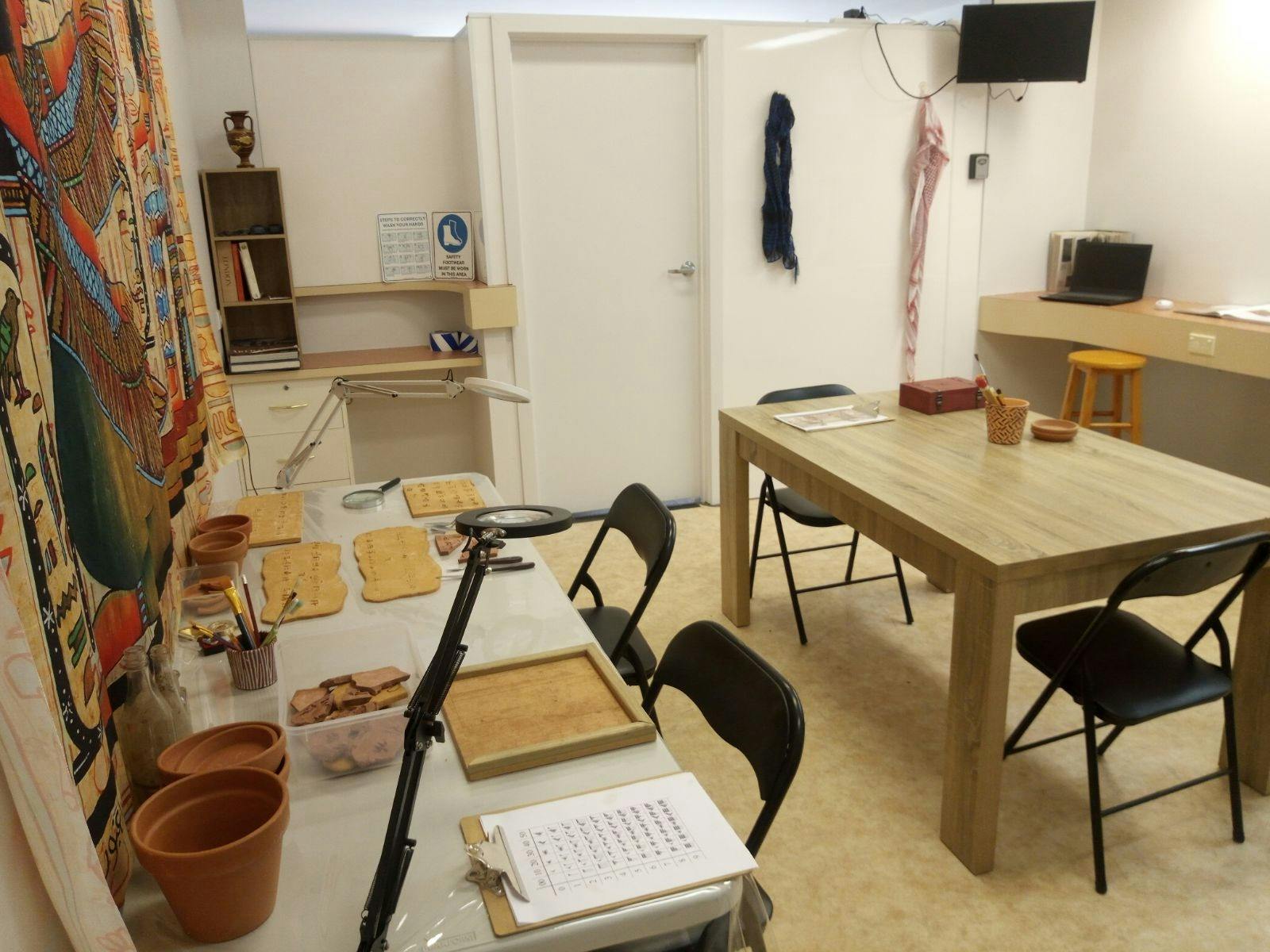 An escape room's workspace with archaeological tools and Mesopotamian-like tablets, invoking the thr