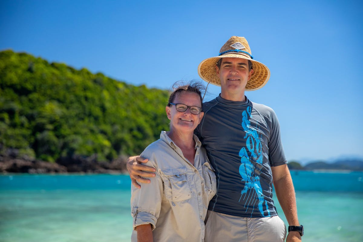 A caucasian womand and man are standing in front of a tropical island