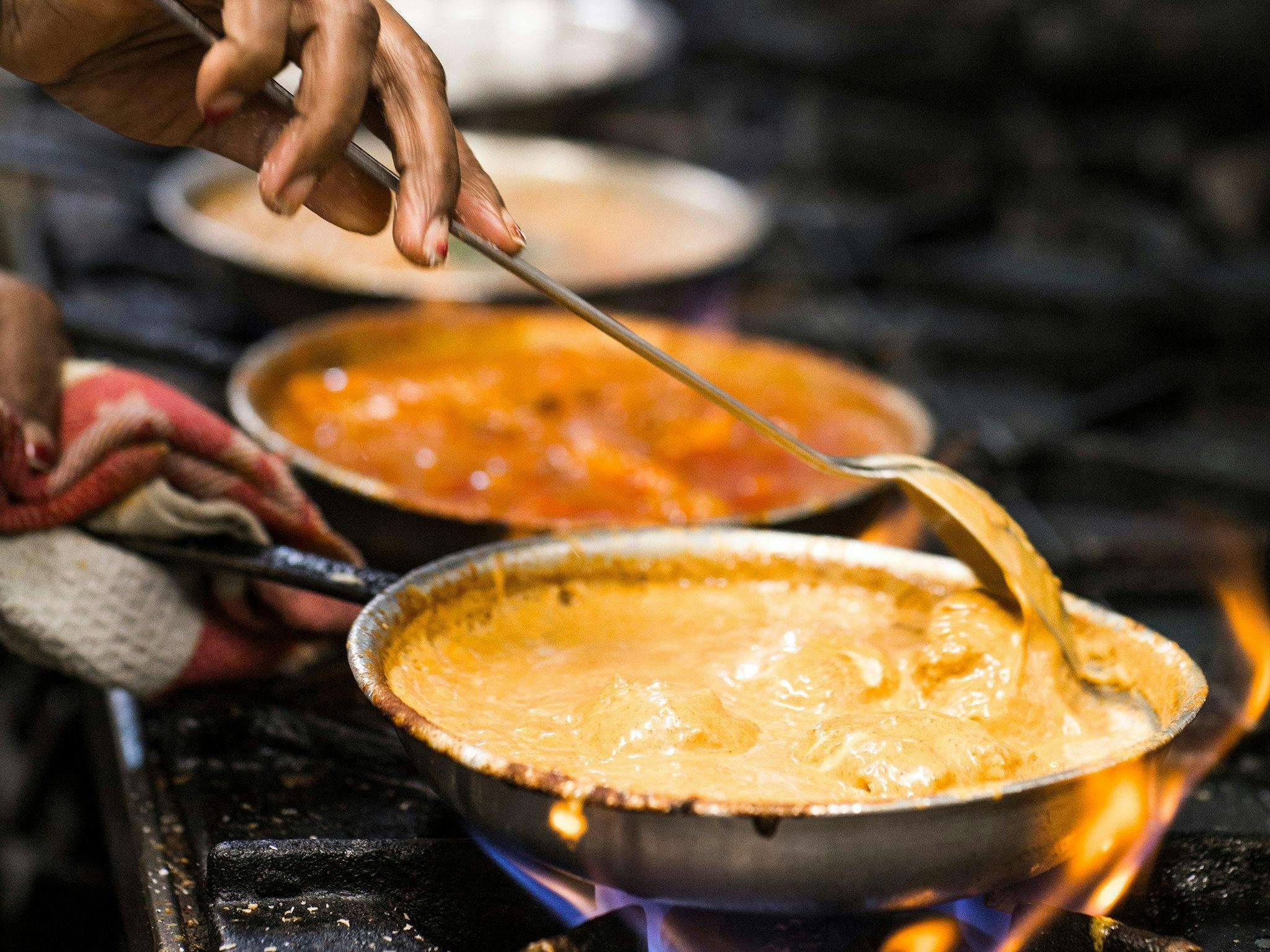 Chef cooking curries on a gas stove