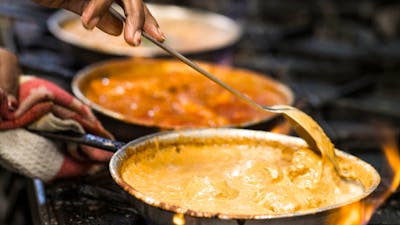 Chef cooking curries on a gas stove