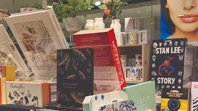 Boxed Stationary and books in foreground, ceramic tumblers and vases with botanical designs on raise